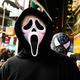 Just a person in a Ghostface costume in Times Square getting photobombed by a person in a Spider-Man costume
